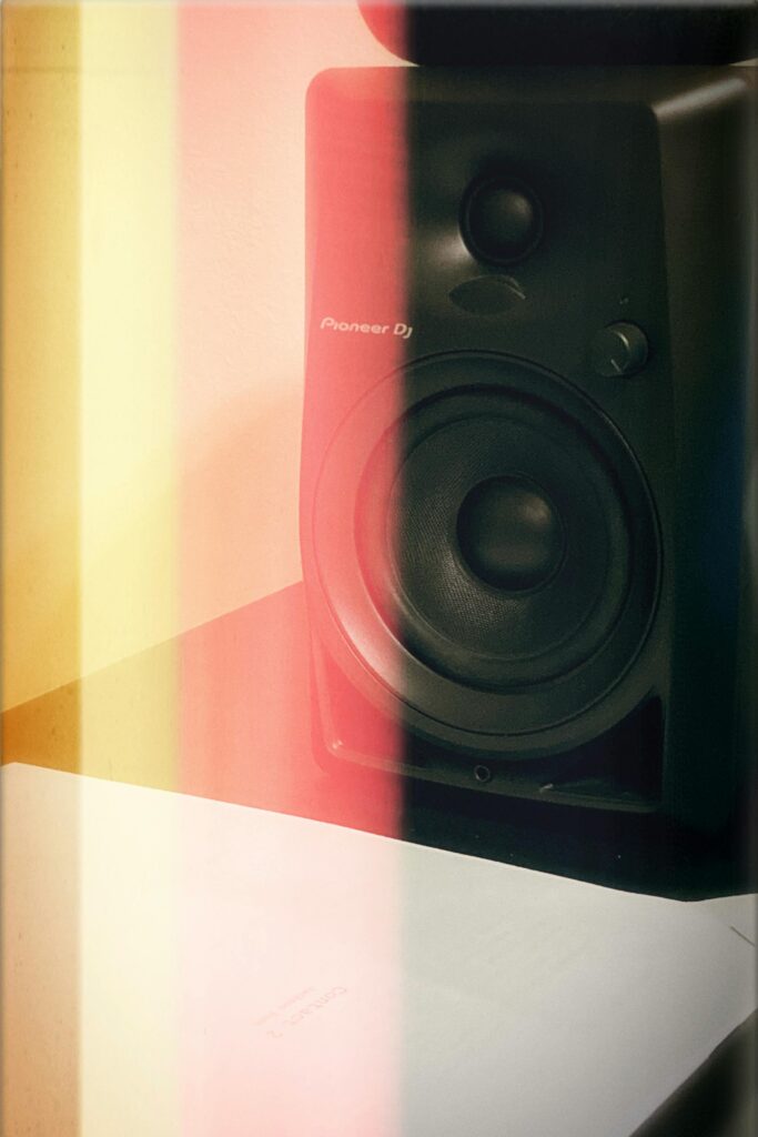 Close-up of a Pioneer DJ speaker on a table with a retro light leak effect, creating a vintage vibe.